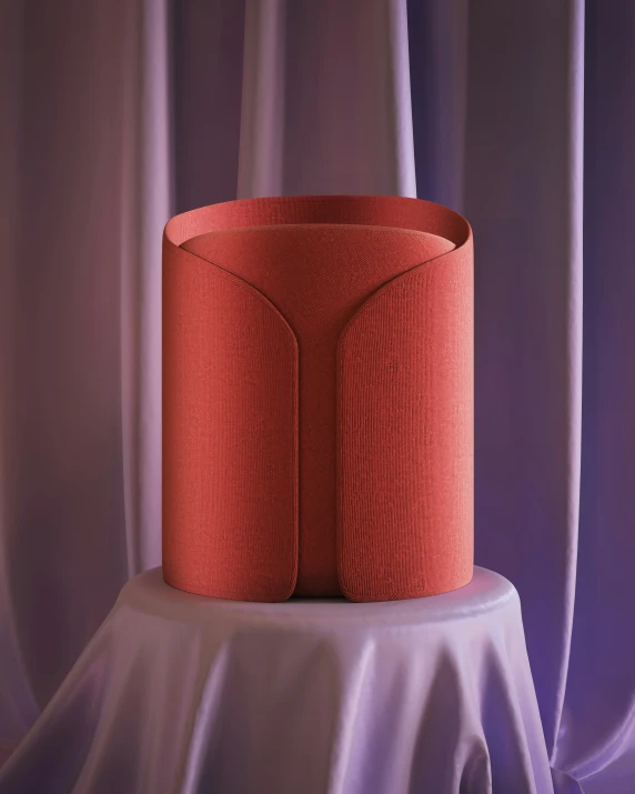 a cylindrical red vase with a piece of wood on it