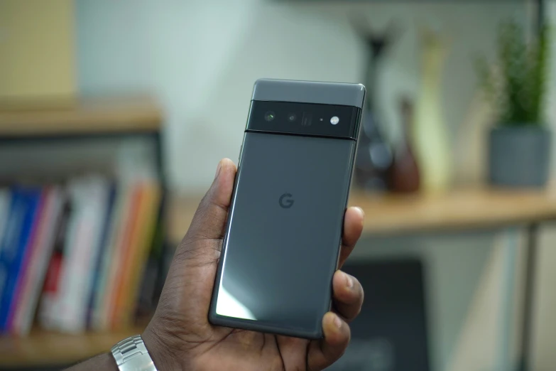 a person holds up a cell phone while it is in front of a book case