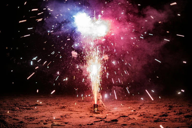 fireworks are lit up over a field of dirt