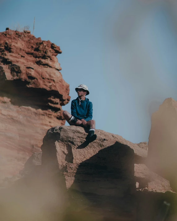 a man sitting on top of a rock next to a rocky landscape