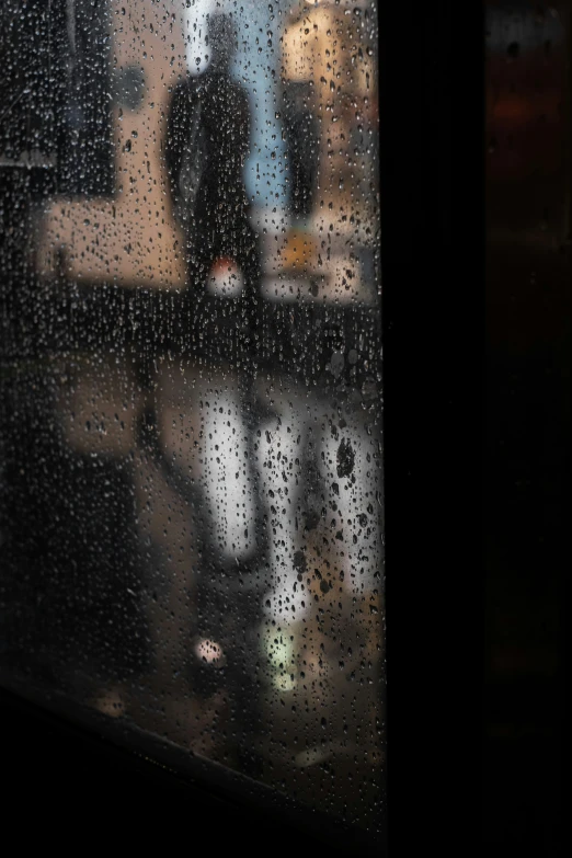 a person standing in front of a wet window