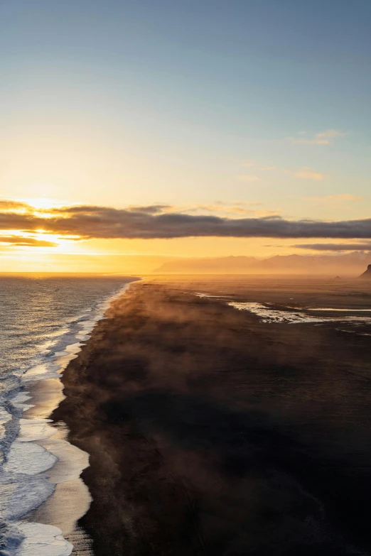 the sun sets over a beach with waves crashing on the shore