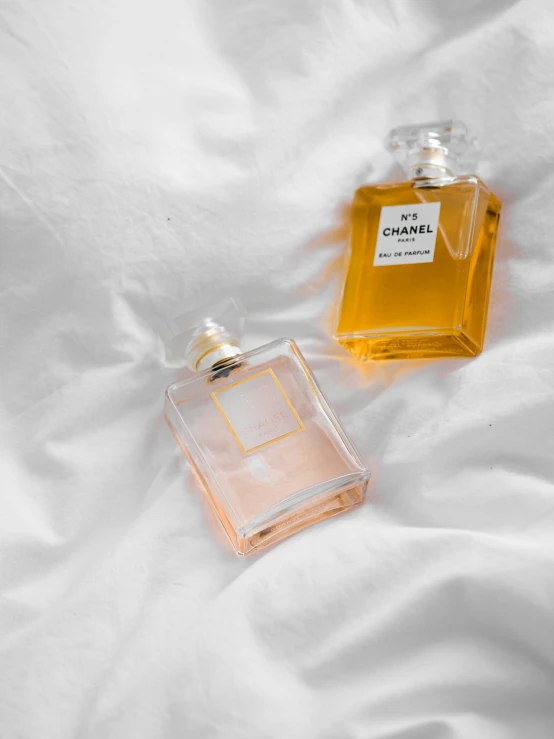 two different bottle shaped perfumes sit on the sheet