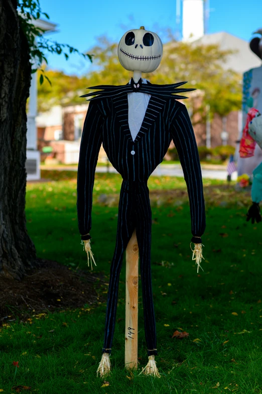 a scarecrow doll is posed on top of a wood pole