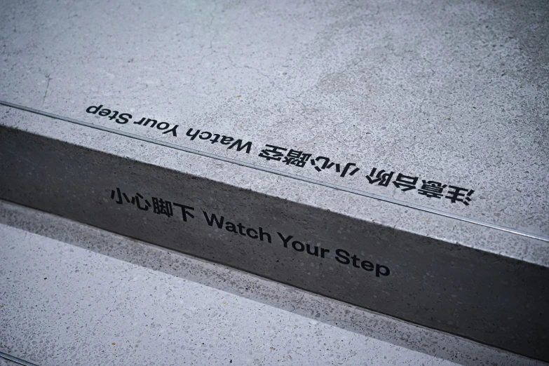 a grey wall with black lettering and an asian language writing on it