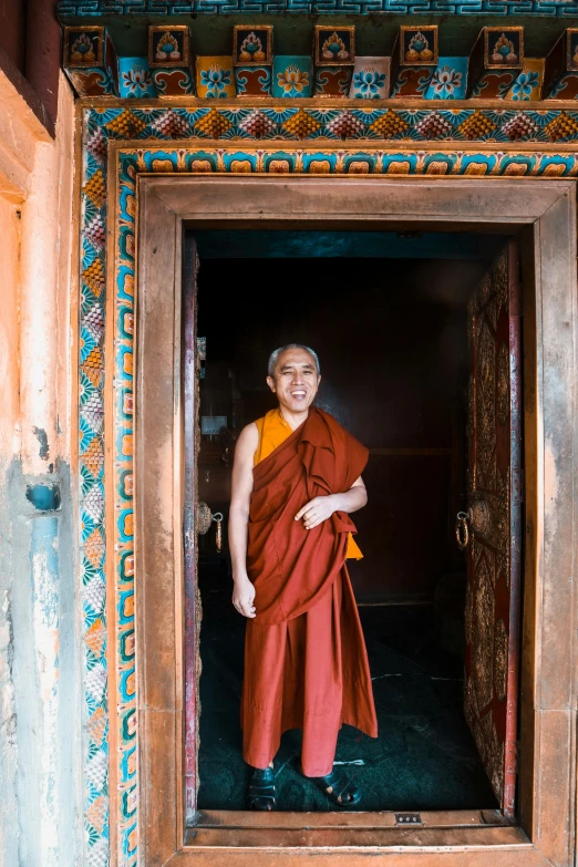 a smiling monk standing inside of an opening in a doorway