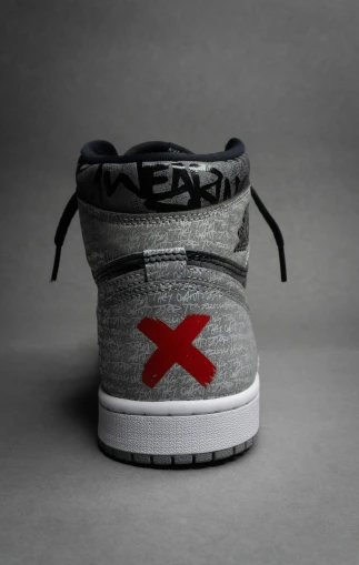 the back side of a gray sneaker that has a x printed on it