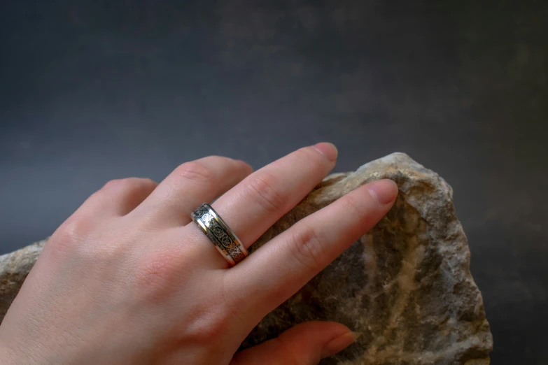 a hand holding onto a stone wearing a band