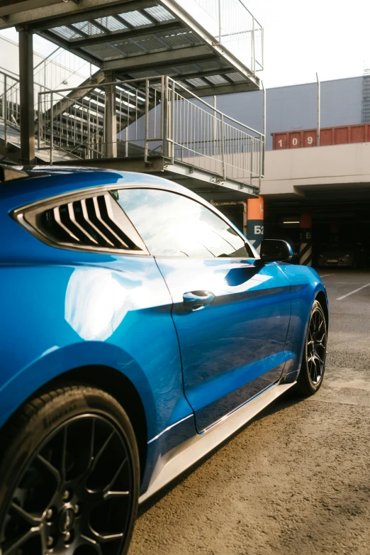 a blue sports car parked in front of an underpass