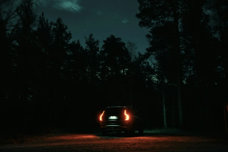 an illuminated car on a dark road with a full moon in the background