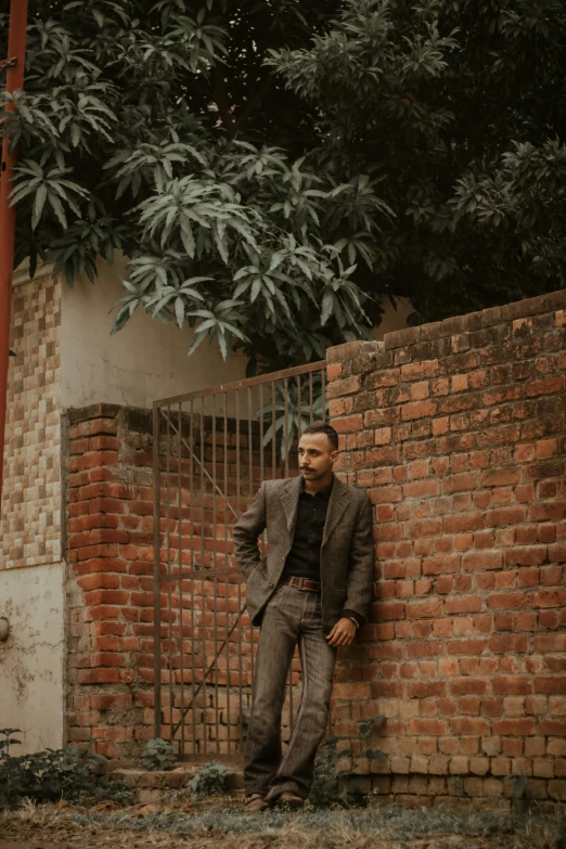 man leaning on brick wall with hand on head looking up