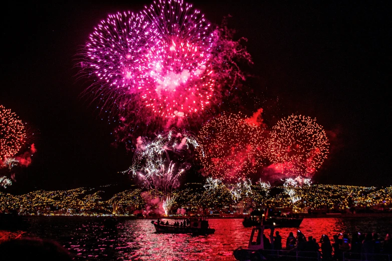 colorful fireworks in the dark sky above a harbor