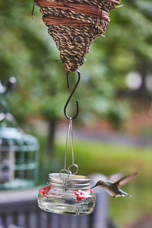 a bird sitting on top of two jar with a bird feeder hanging from it