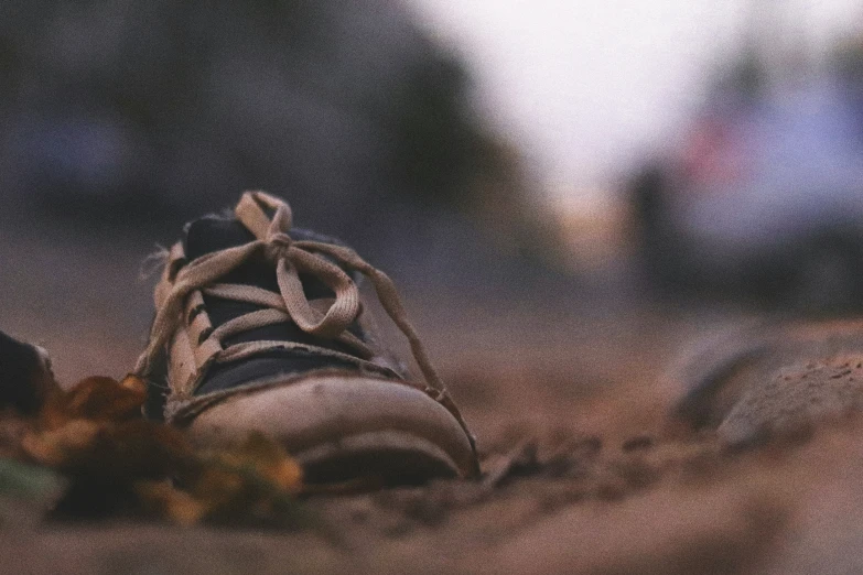 an old worn shoes rests on a sidewalk