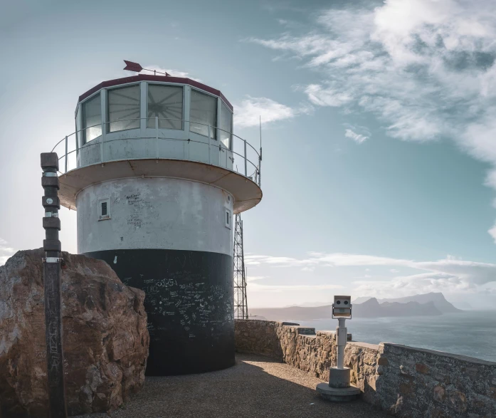 an old lighthouse and a rock on the edge of a cliff