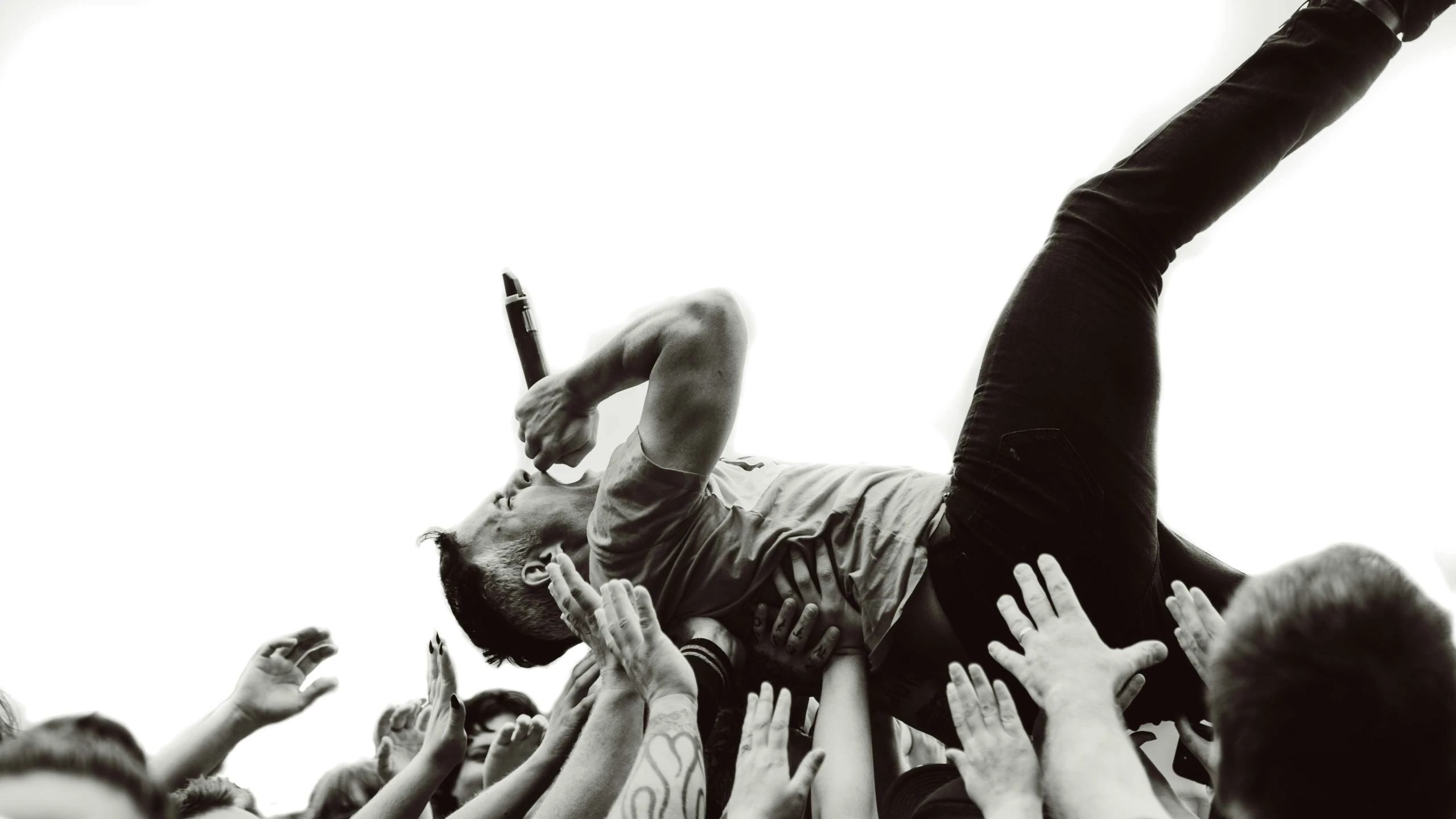 a man in black shirt and arms raised in front of an audience