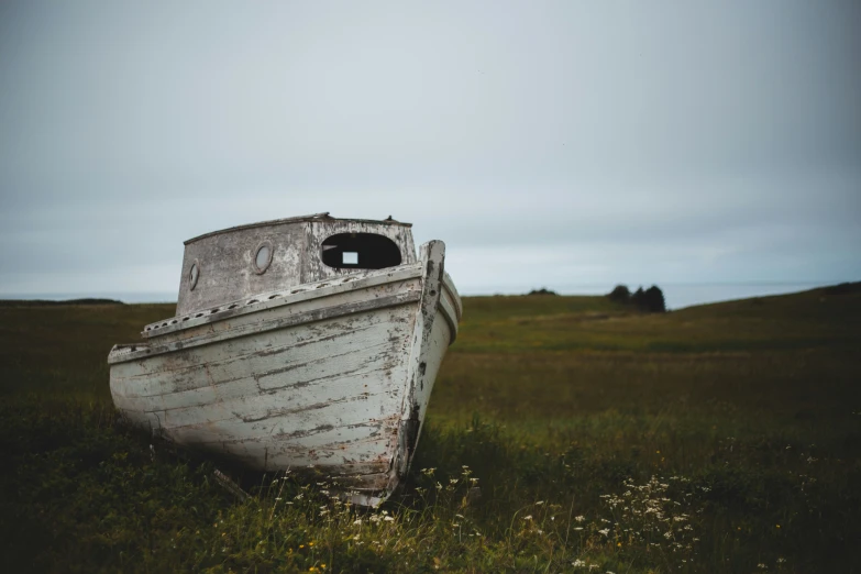 an old boat that is on the grass in the field