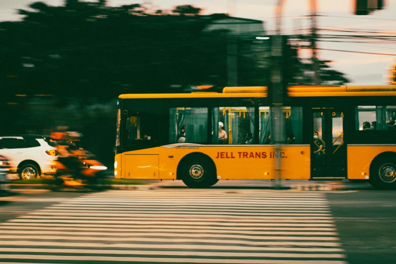 a yellow bus driving down a road next to cars