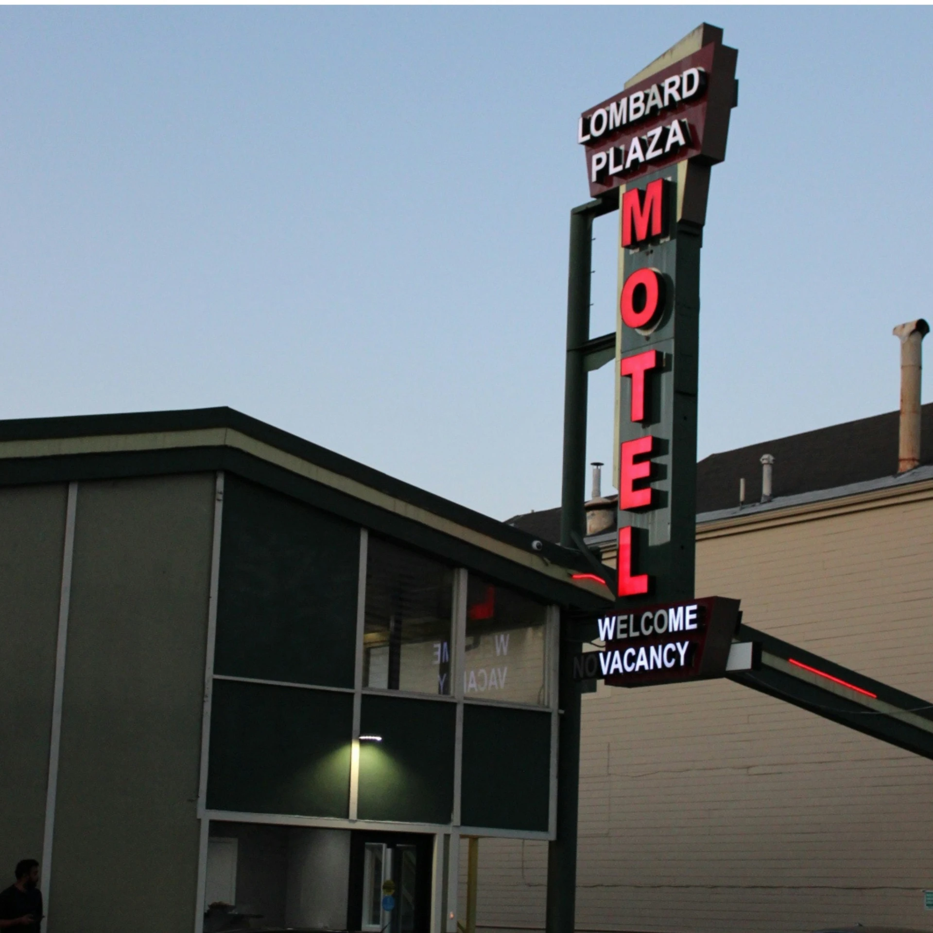 motel with bright red sign hanging from it's tall, brick building