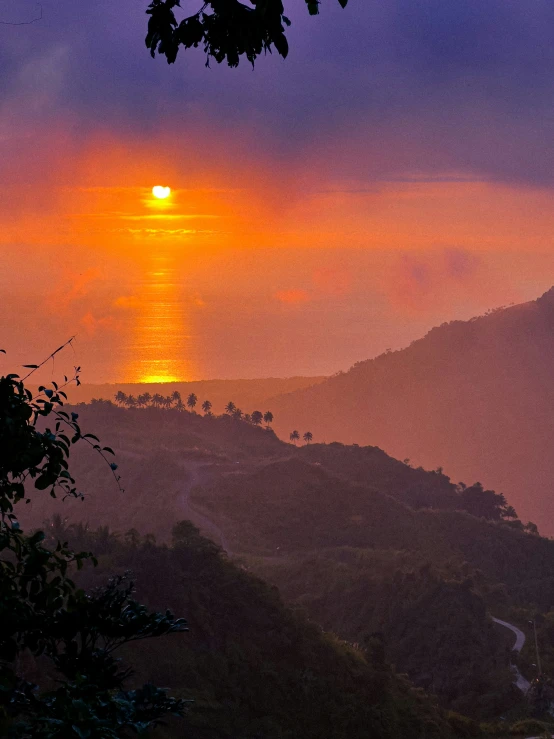 a view of the sun setting over the hills