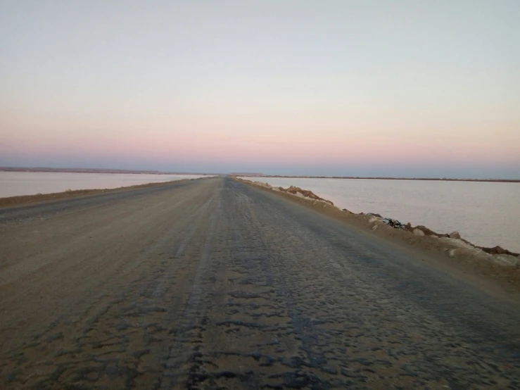 a dirt road with two cars traveling on it