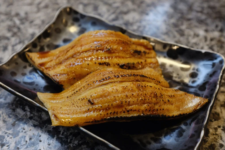 fried fish on a black dish sitting on a granite countertop