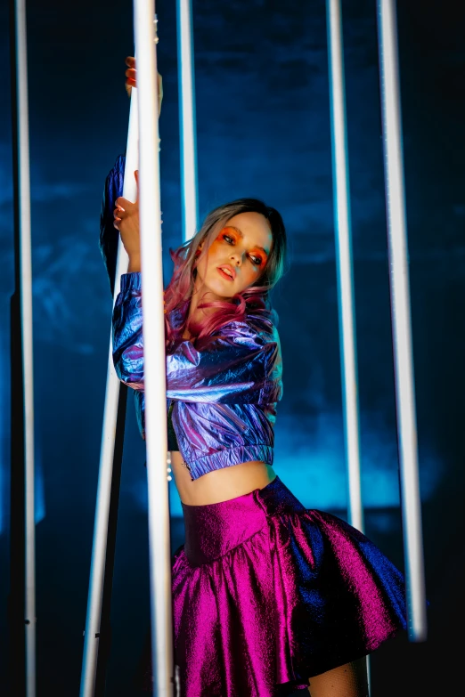 a woman wearing shiny clothes poses behind poles