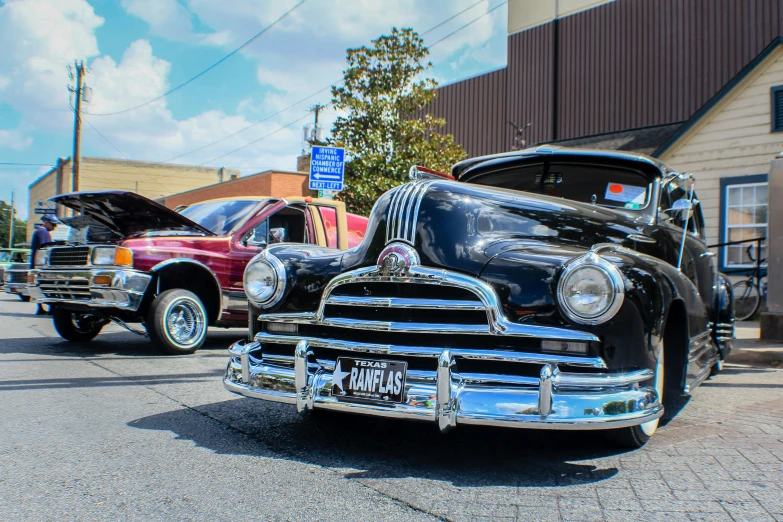 an old fashion black car in the street with other vintage cars
