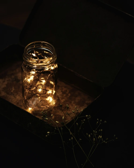 lighted jars in the dark on top of an old box