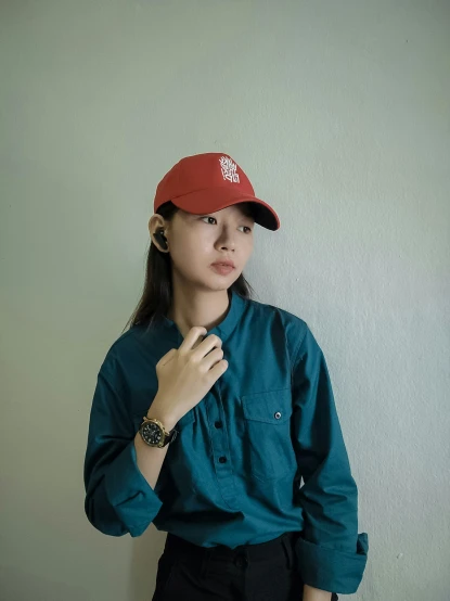 a woman poses in a green shirt and red baseball hat