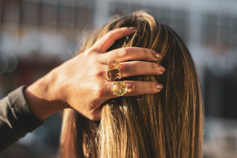 woman's hand with diamond rings on her head and long blonde hair