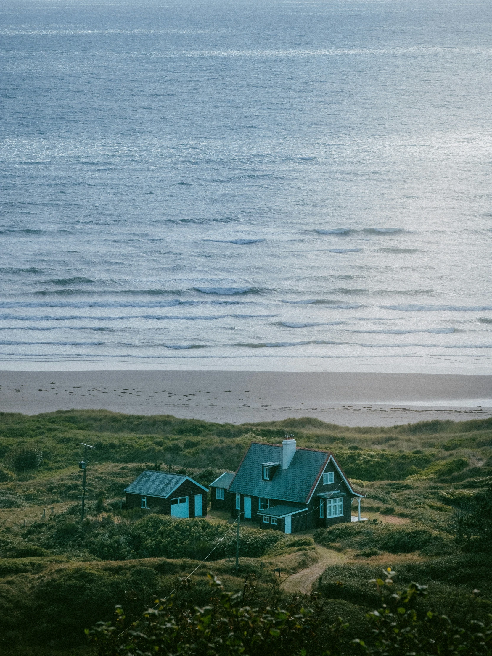 a house is sitting on the side of a beach