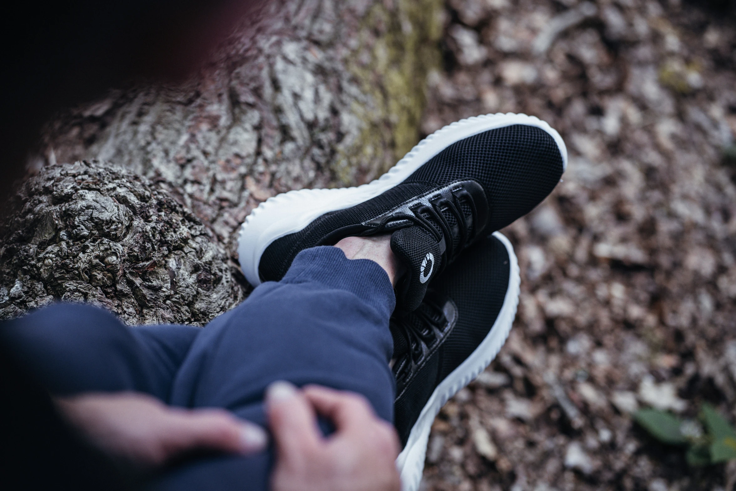 a person standing next to a tree trunk with their shoes off