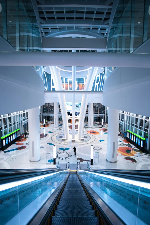 two escalators leading down to a building with tv screens