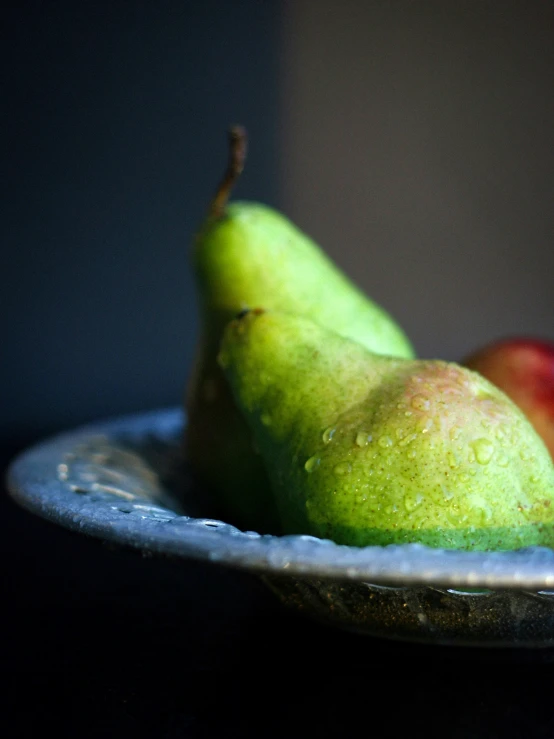 two pears and one piece of fruit in a dish