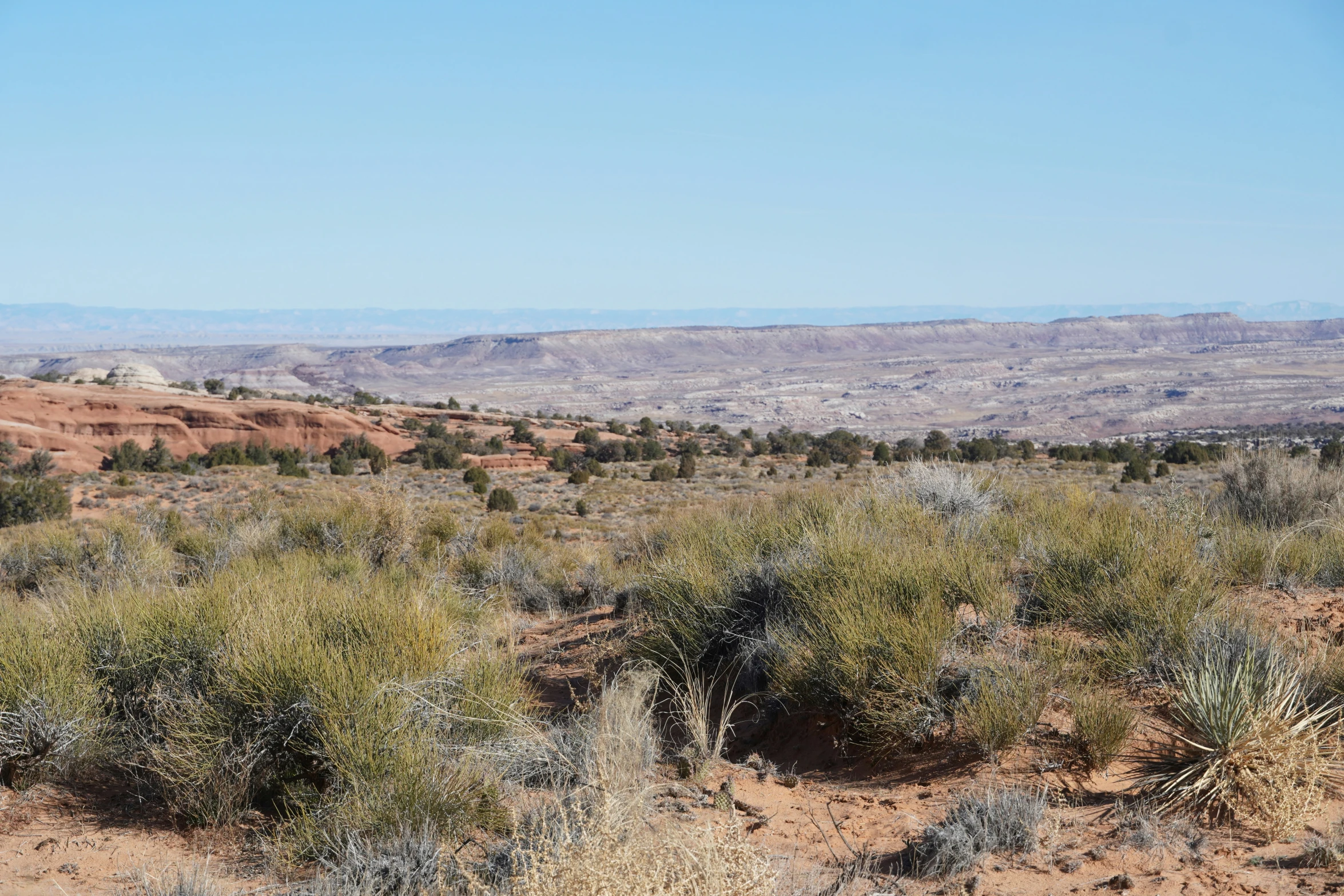 a desert field surrounded by mountains under a blue sky