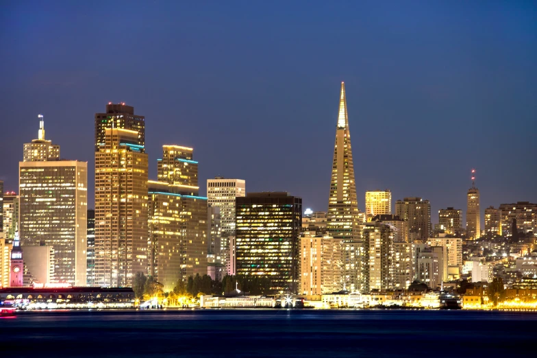 a city skyline at night with bright lights reflecting off of water