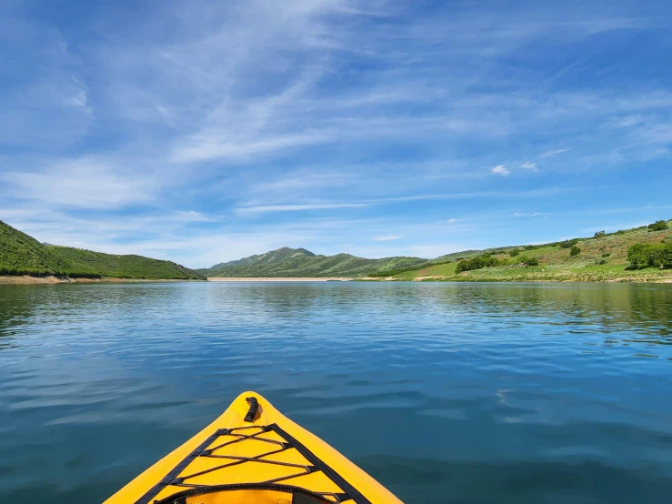 a yellow canoe sitting on top of a lake near mountains