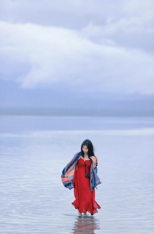 woman in a red dress standing in shallow water, facing the camera