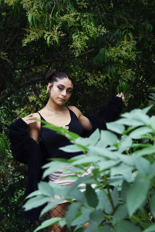 a woman with black dress and necklace posing in a tree