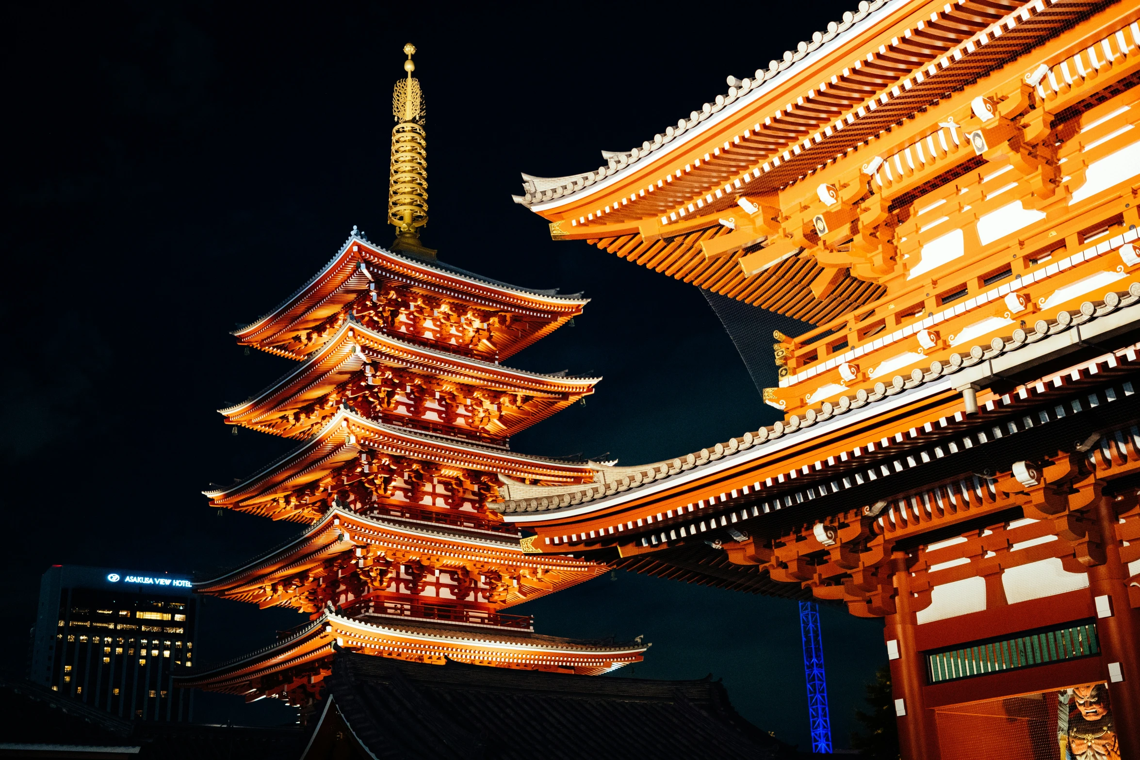 three tall asian buildings illuminated at night