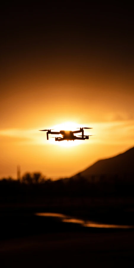 an airplane is flying into the sunset with a mountain in the background