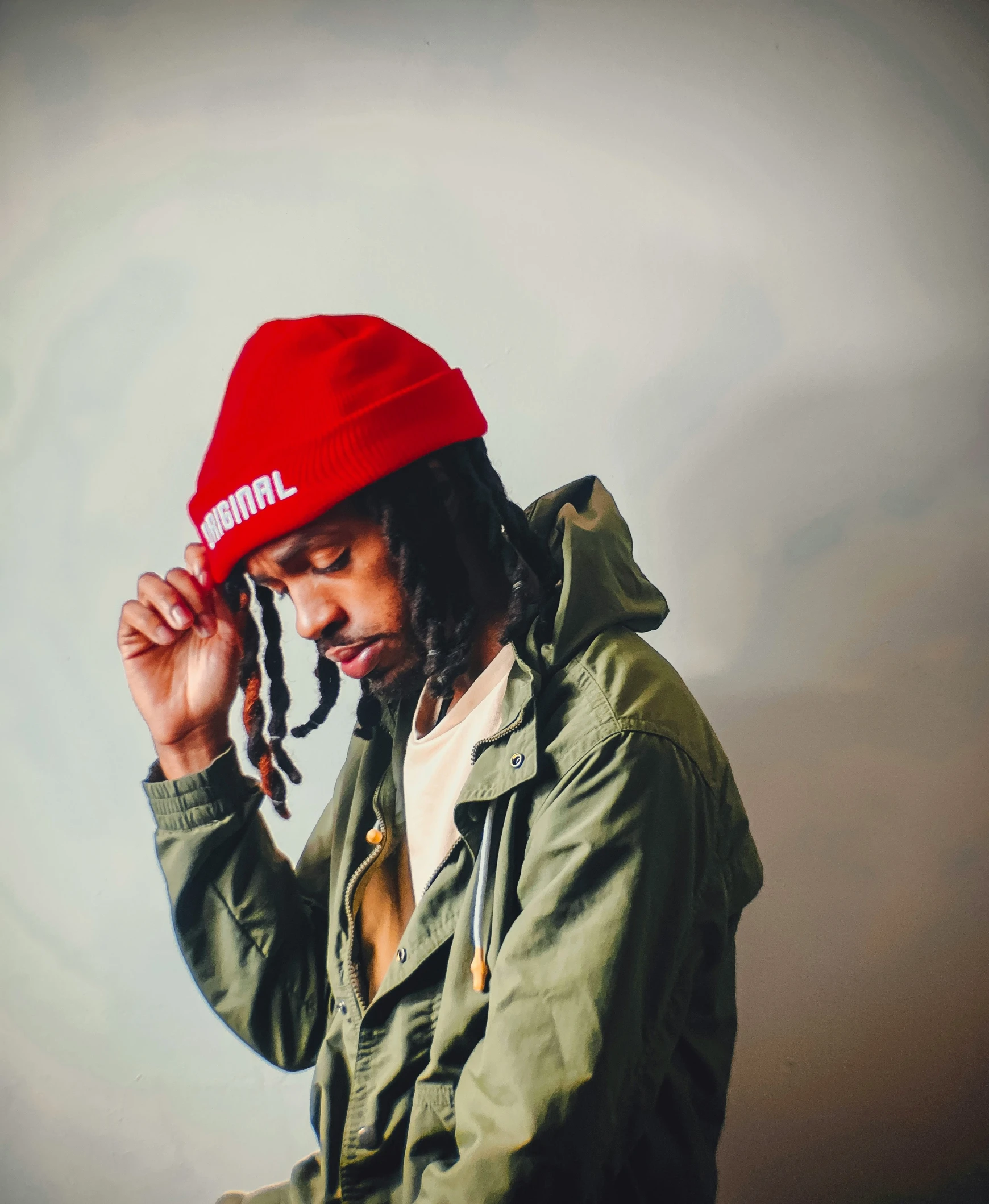 a young man with dreadlocks covers his head with his hands