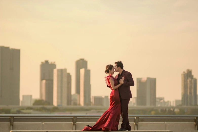 a young man and woman are emcing each other while standing in front of a bridge