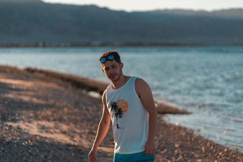 there is a male with a white shirt and blue shorts standing by the water