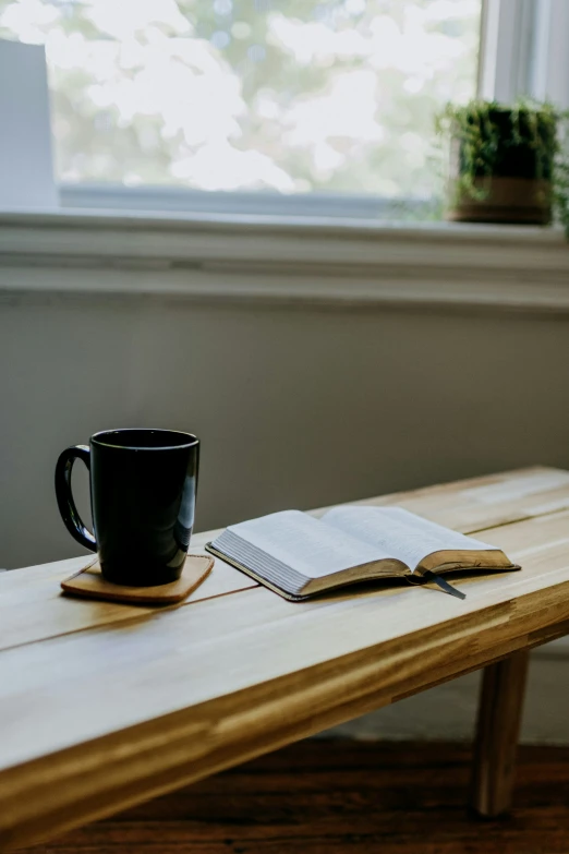 there is a book, coffee mug and an open book on the table