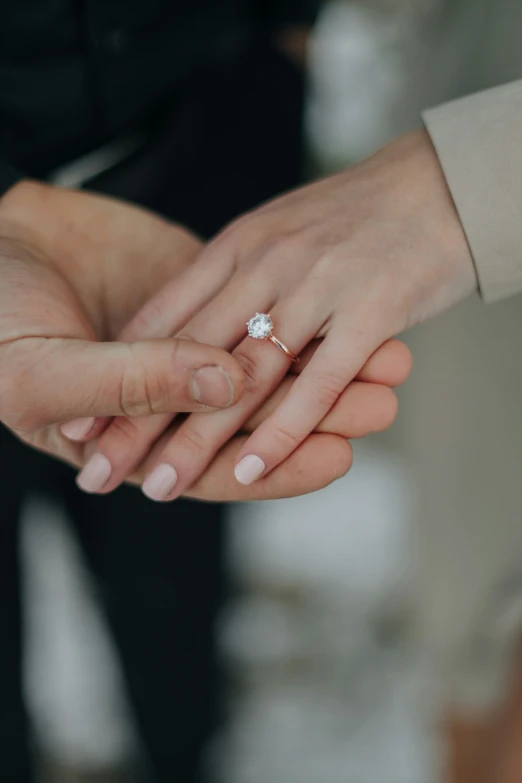 a man and woman's hands are holding a diamond ring