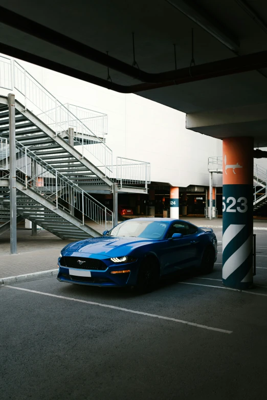 a blue car parked in a parking lot next to a set of stairs