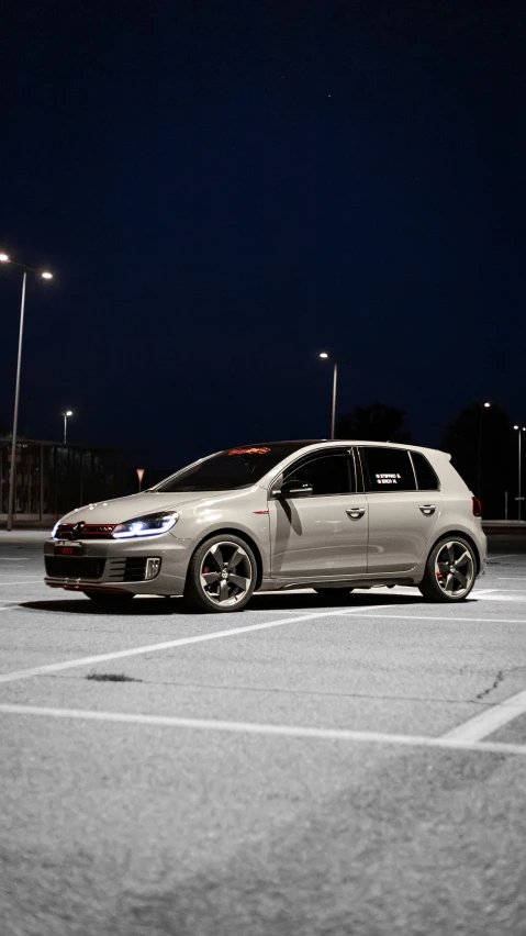 a parked white car sitting in a parking lot at night