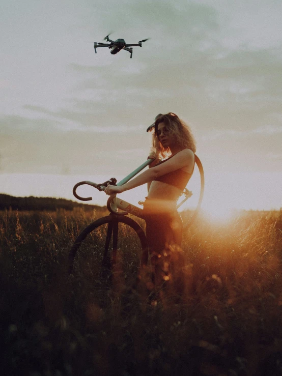 a woman with long hair is standing next to her bicycle and a flying device